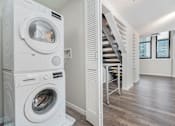 Thumbnail 18 of 32 - A white washing machine and dryer in a laundry room.