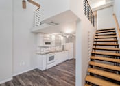 Thumbnail 14 of 32 - A modern kitchen with white appliances and wooden stairs.