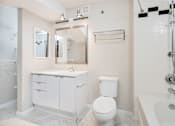 Thumbnail 16 of 32 - A white bathroom with a toilet, sink, and bathtub.