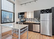 Thumbnail 11 of 32 - A modern kitchen with a granite countertop and stainless steel appliances.