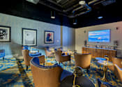 Thumbnail 25 of 32 - A room with blue chairs and a television on the wall.