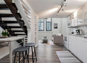 Thumbnail 7 of 32 - A modern kitchen with white cabinets and a wooden floor.
