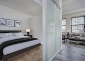 Thumbnail 9 of 32 - A bedroom with a large bed and a couch in the background.