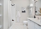 Thumbnail 10 of 32 - A white bathroom with a toilet, sink, and a shower curtain.