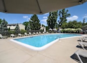 Thumbnail 24 of 28 - A large outdoor swimming pool surrounded by lounge chairs and trees.