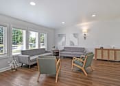 Thumbnail 2 of 28 - A living room with a grey couch, a green armchair, and a wooden table.