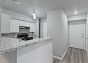 Thumbnail 5 of 23 - A kitchen with a granite countertop and white cabinets.