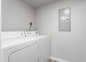 Thumbnail 14 of 23 - A white washing machine and dryer in a small laundry room.