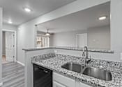 Thumbnail 4 of 23 - A modern kitchen with granite countertops and stainless steel appliances.