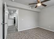 Thumbnail 9 of 23 - A room with a ceiling fan and a door leading to another room.
