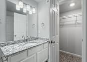 Thumbnail 13 of 23 - A bathroom with a granite countertop and a white door.
