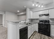 Thumbnail 17 of 23 - A kitchen with black appliances and white cabinets.