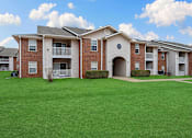 Thumbnail 21 of 23 - Apartment complex with red brick buildings and green lawns.