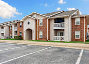 Thumbnail 23 of 23 - Apartment building with a parking lot in front.