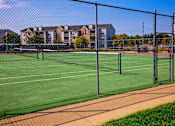 Thumbnail 22 of 29 - A tennis court surrounded by a fence.
