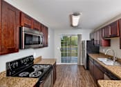 Thumbnail 1 of 29 - A kitchen with a black stove top oven and wooden cabinets.