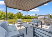Thumbnail 20 of 29 - A patio with grey couches and a table under a roof.