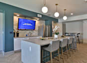 Thumbnail 15 of 38 - A modern kitchen with a bar area and a television screen mounted on the wall.