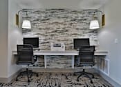 Thumbnail 20 of 38 - Two black chairs are positioned in front of a white desk with a laptop and monitor on it.