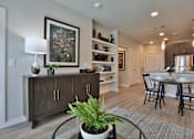 Thumbnail 6 of 38 - A modern living room with a wooden cabinet, a potted plant, and a framed picture on the wall.