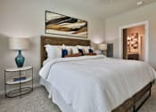 Thumbnail 5 of 38 - A bedroom with a large bed, a nightstand with a lamp, and a painting on the wall.