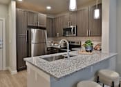 Thumbnail 2 of 38 - A kitchen with a granite countertop and stainless steel appliances.