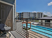 Thumbnail 11 of 38 - A balcony with a chair and a pool in the background.