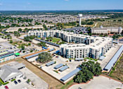 Thumbnail 31 of 32 - An aerial view of a large building complex with a parking lot in front.