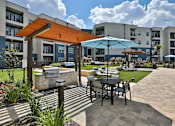 Thumbnail 22 of 32 - A patio with a table and chairs is surrounded by apartment buildings.
