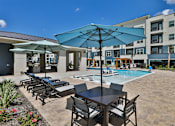 Thumbnail 21 of 32 - A poolside area with chairs and umbrellas.