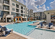 Thumbnail 19 of 32 - A swimming pool surrounded by chairs and buildings.