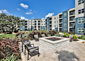 Thumbnail 23 of 32 - A sunny day at a residential complex with a fountain in the middle of a patio.