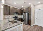 Thumbnail 9 of 32 - a kitchen with a granite counter top and a stainless steel refrigerator