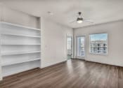 Thumbnail 11 of 32 - an empty living room with white walls and wood floors and a window with white shelves