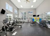Thumbnail 23 of 30 - a gym with cardio machines and windows and a ceiling fan