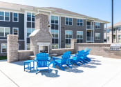 Thumbnail 26 of 30 - a patio with blue chairs and a fire pit