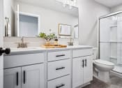 Thumbnail 9 of 30 - a bathroom with white cabinets and a toilet and a shower