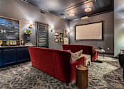 Thumbnail 29 of 43 - A living room with a red couch and a grey car poster on the wall.
