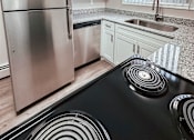Thumbnail 2 of 34 - A modern kitchen with a stainless steel refrigerator and black stove top.