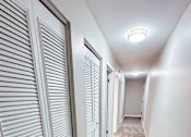 Thumbnail 10 of 34 - A long hallway with white doors and carpeted floors.
