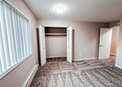 Thumbnail 6 of 34 - A room with a carpeted floor and a window with blinds.
