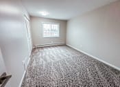 Thumbnail 7 of 34 - A room with a carpeted floor and a window with blinds.
