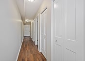 Thumbnail 18 of 34 - a hallway with white closets and wood floors