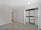 Thumbnail 20 of 34 - a bedroom with white walls and a closet with a mirrored door