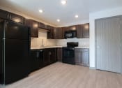 Thumbnail 20 of 30 - an empty kitchen with black appliances and dark wood cabinets