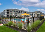 Thumbnail 29 of 30 - a pool with chairs and an umbrella in front of an apartment building