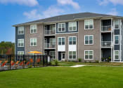 Thumbnail 28 of 30 - an apartment building with a green lawn and a fence
