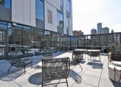 Thumbnail 4 of 29 - a rooftop patio with tables and chairs and a city in the background