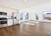 Thumbnail 19 of 29 - an empty living room with a kitchen and a large window