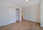 Thumbnail 20 of 29 - a bedroom with white walls and wood flooring and a closet